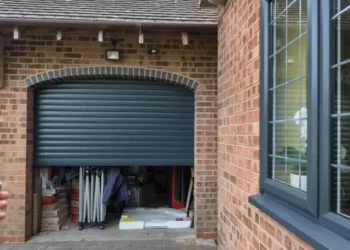 انواع کرکره برقی بسیار دنیای گسترده ای است.کرکره برقی مشکی رنگ، که برای یک گاراژ نصب شده و فردی در حال باز کردن آن با ریموت است.