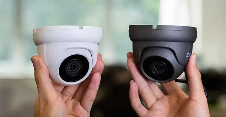 دو دوربین دام سفید و مشکی که در دست های یک فرد قرار گرفته اند