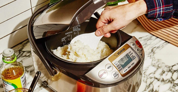فردی در حال کشیدن برنج پخته شده در دستگاه پلوپز. پلوپز جز لوازم پخت و پز برقی می ‌باشد که به واسطه آن می‌توان انواع مختلفی از خورش و کیک را طبخ نمود.
