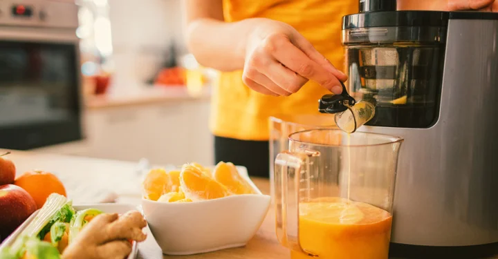 فردی در حال تهیه آب پرتقال به وسیله دستگاه آبمیوه گیری می‌باشد.