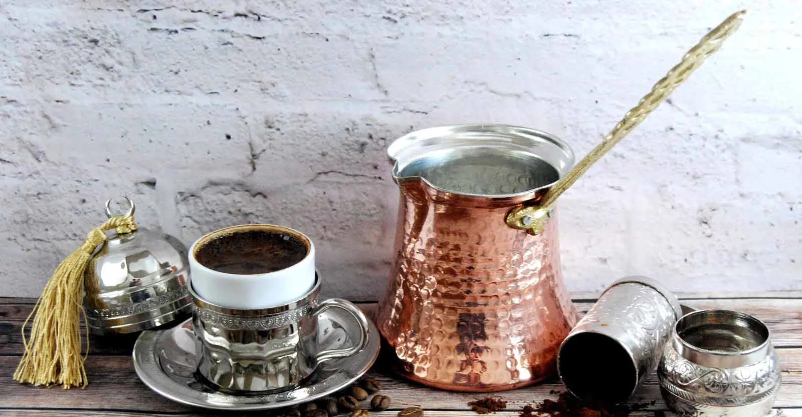 قهوه جوش ترک مسی که در کنار یک لیوان قهوه قرار گرفته است.
