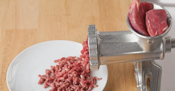 یک عدد چرخ گوشت که داخل محفظه آن گوشت های خرد شده قرار گرفته است و گوشت های چرخ شده از آن در حال خارج شدن هستند. | مجله برقیجات