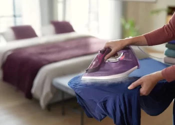 فردی در حال اتوکشی یک پیراهن آبی است. | برقیجات