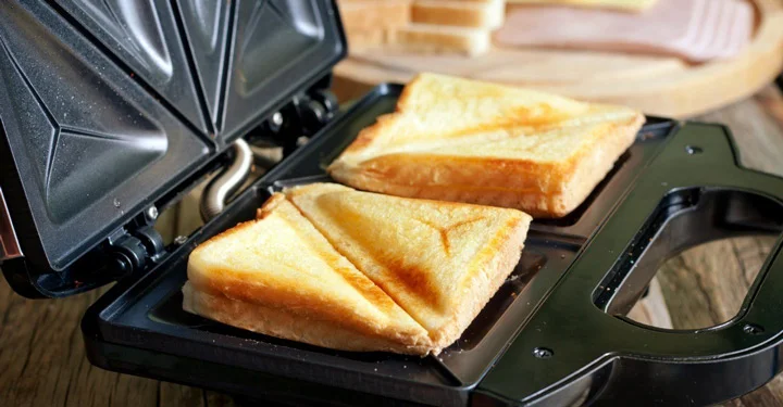 دو عدد نان تست که در حال تست شدن به وسیله دستگاه ساندویچ ساز هستند.